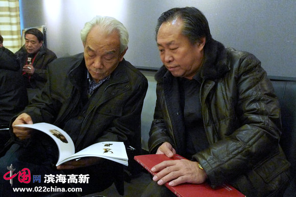 河西区政协副主席刘国胜与著名画家纪振民在观看画册。