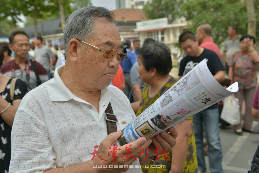 第四届“天穆杯”书画摄影展在北辰区天穆东苑举行，图为观众阅读《天穆书画摄影报》。