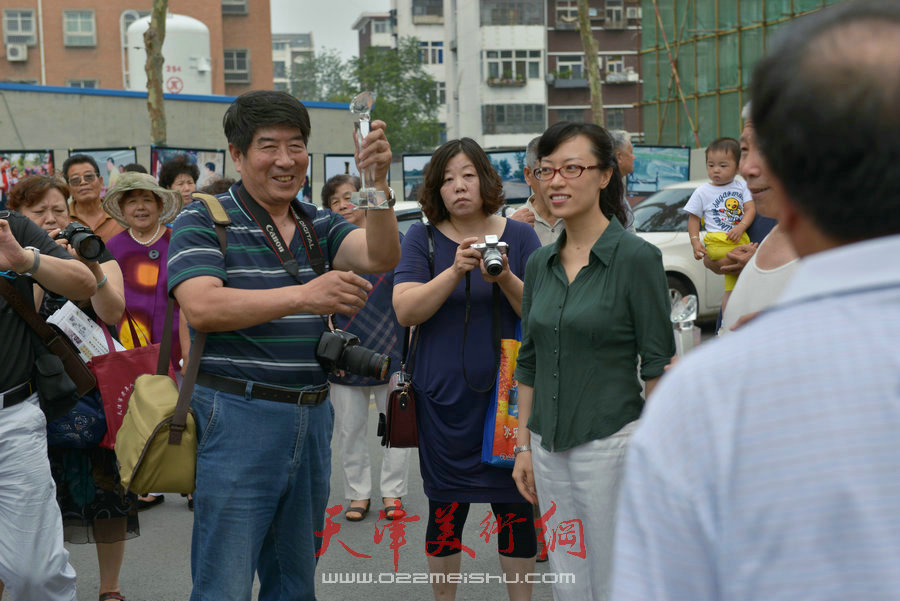 第四届“天穆杯”书画摄影展在北辰区天穆东苑举行，图为获奖者高举奖杯。