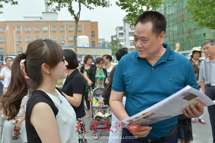 第四届“天穆杯”书画摄影展在北辰区天穆东苑举行，图为穆祥友与观众交谈。